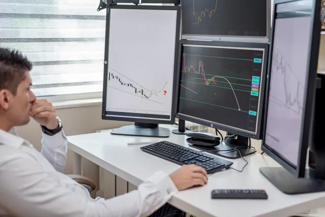 Business professional analyzing financial data on multiple computer monitors at his workspace. Preismodelle für Software-Abos: Nutzer, Verbrauch und Staffelungen
