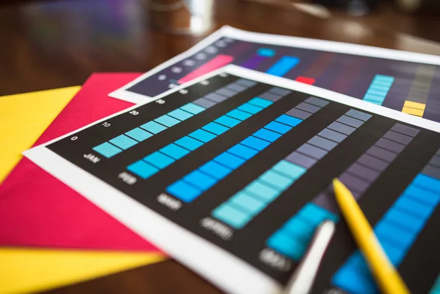 Close-up of colorful financial charts and a pencil on a wooden desk. Named User o Concurrent User: confronto tra le metriche di licenza
