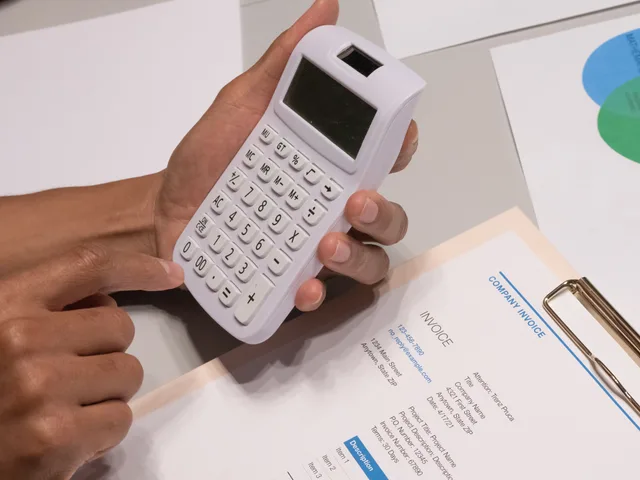 Close-up of hands using a calculator next to a company invoice, depicting a financial calculation concept. Verifica delle fatture SaaS: voci, valuta e IVA