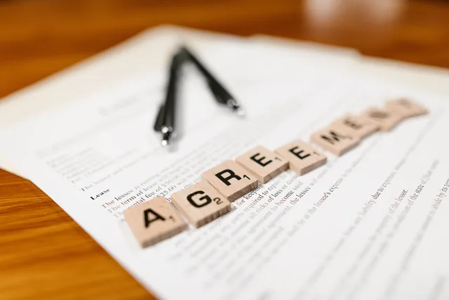 Scrabble tiles spelling 'AGREEMENT' on a lease document, emphasizing contractual themes. Livelli di servizio nei contratti SaaS: disponibilità, supporto e sanzioni